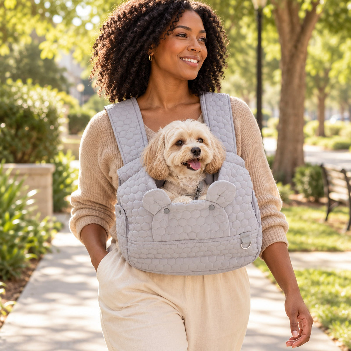 Person wearing the quilted gray front carrier with a small dog looking out of the open top