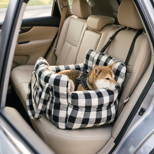 Small dog resting in a black check pet car bed strapped to a car seat
